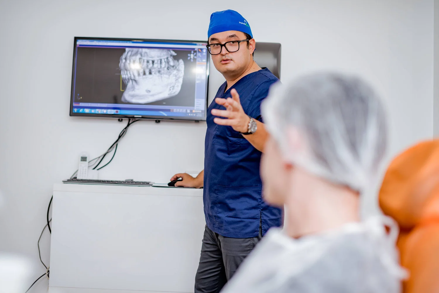 Dr. Olgun Chemal îi explică unui pacient reconstrucția 3D a CBCT-ului pe ecran